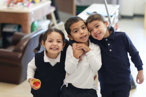 Three three year old students smiling at the camera