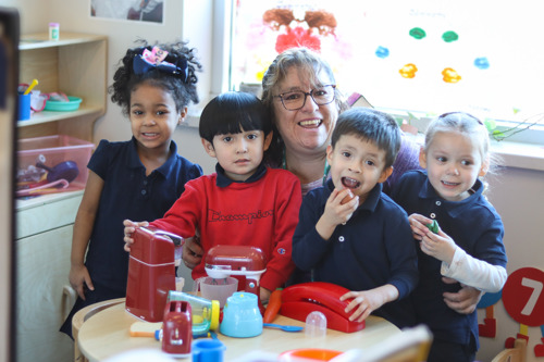 Female teacher smiling at a classroom table with her students